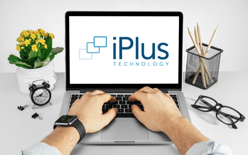 Vemos una persona utilizando una computadora con el logo del software iPlus ERP.